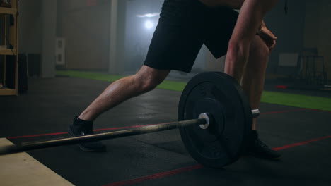 slow motion: man doing single-arm landmine squat-to-press exercise. young man lifting barbell with light weights at gym