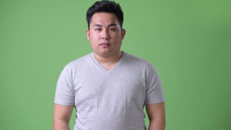 초록색 배경에 젊은 잘생긴 과체중 아시아인