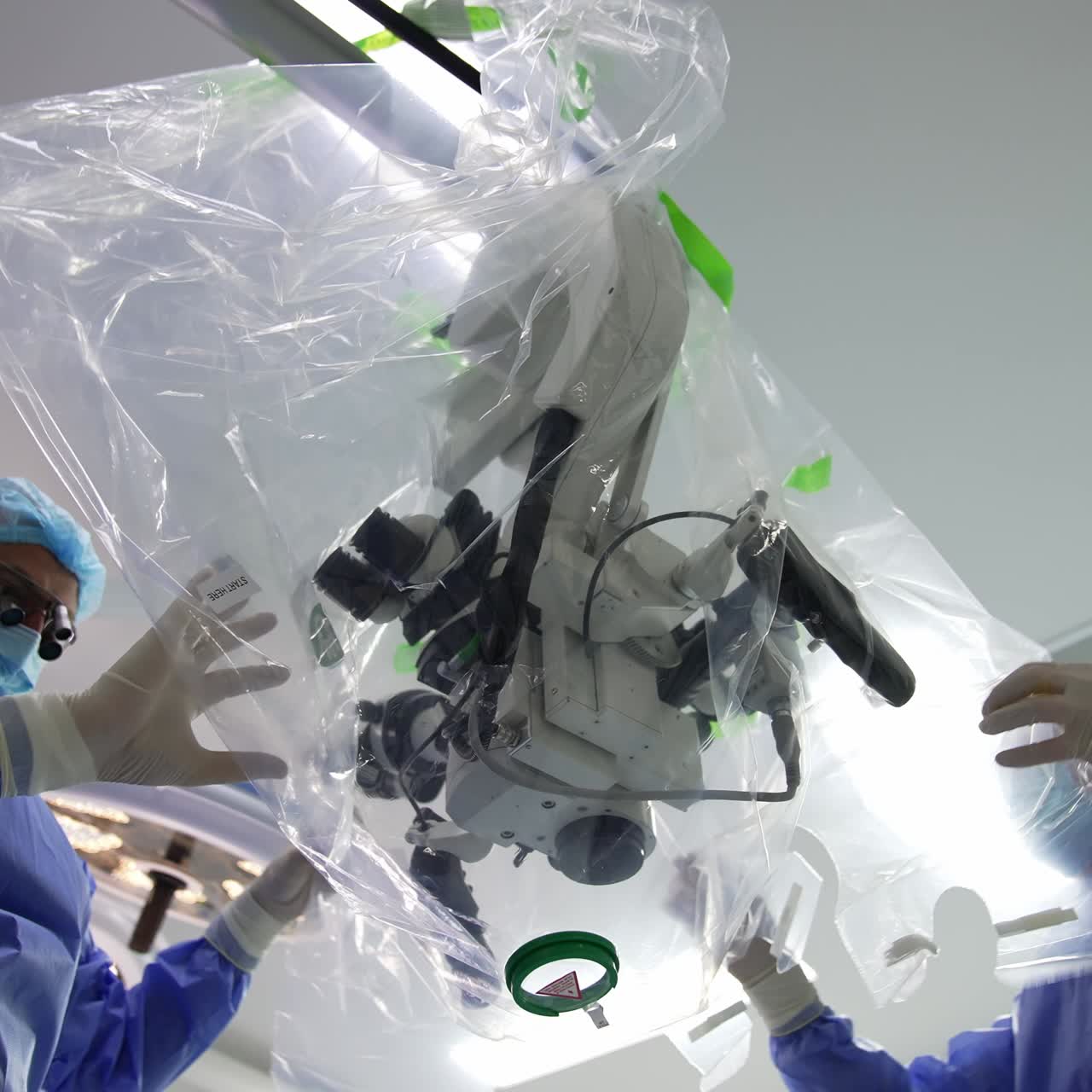 Putting on plastic cover on the high precise technological equipment. Preparation of the microscope for usage at surgical operation. Low angle view