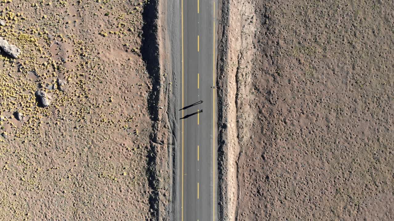 아타카마 사막에서 일출 때 도로에 있는 두 명의 여행자의 공중 평면도