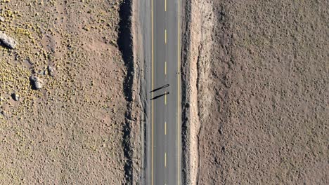 Aerial-top-view-of-two-travelers-in-a-road-at-sunrise-in-Atacama-Desert