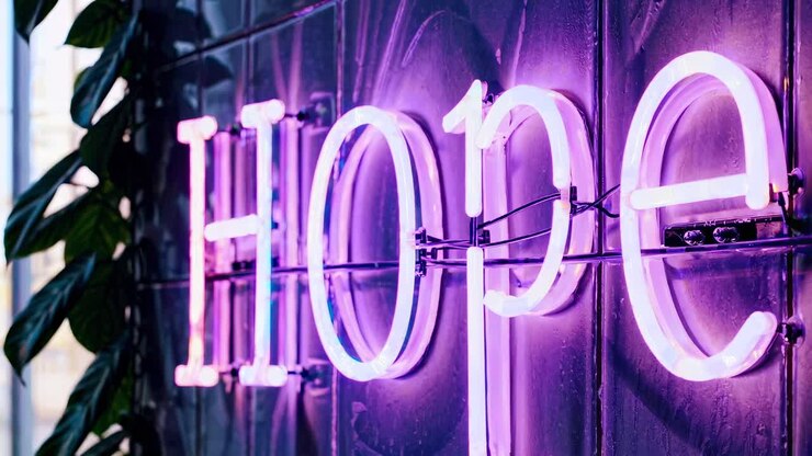 Neon sign spelling &#039;Hope&#039; in vibrant pink and purple, captured from a side angle