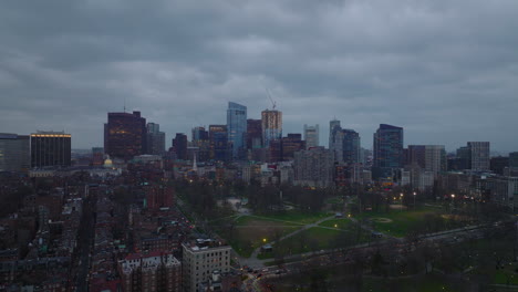 Backwards-fly-above-urban-district.-Group-of-modern-high-rise--office-buildings-against-overcast-sky-at-dusk.-Boston,-USA