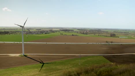 a wind turbine in a rural landscape on a sunny day, casting a long shadow, aerial view