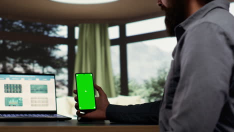 Male-billionaire-uses-greenscreen-phone-display-at-desk