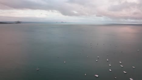 Sailboats-parked-Port-Airlie-Beach-Bay-Lagoon-Coral-Sea-marina-aerial-drone-rain-clouds-mist-sunrise-morning-heart-of-Great-Barrier-Reef-Whitsundays-Whitehaven-jetty-yachts-forward-motion