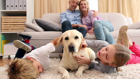 hermanos felices acariciando a un labrador en la alfombra