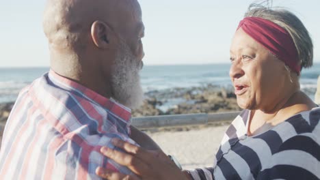 Happy-senior-african-american-couple-embracing-on-promenade-by-the-sea,-slow-motion