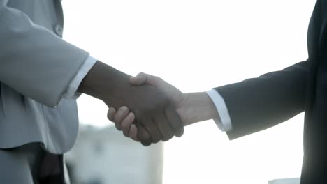 closeup shot of colleagues shaking hands on street