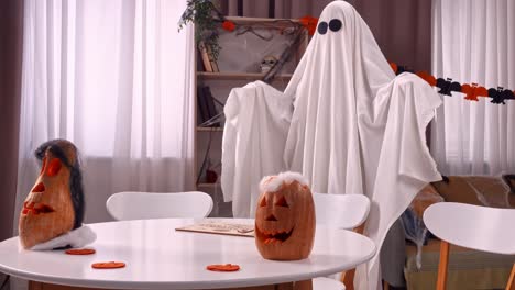 family celebrating halloween with ghost costumes and jack-o'-lanterns