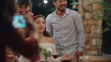 Amigos-De-Una-Cena-Posando-Para-Una-Foto-Celebrando-La-Amistad-Disfrutando-De-Una-Reunión-Creando-Recuerdos-En-Una-Noche-De-Verano-Al-Aire-Libre-4k