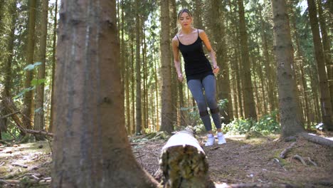 Low-angle-view-of-a-woman-jumping-across-a-log-as-part-of-her-fitness-routine-in-a-park