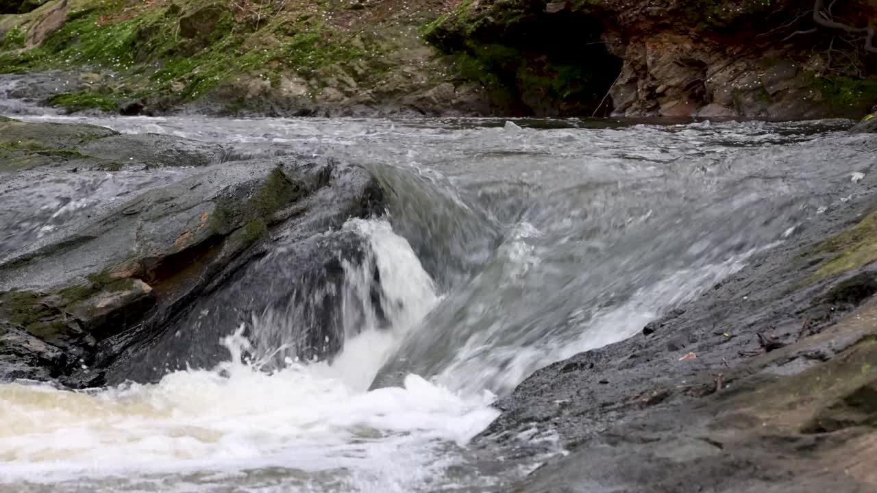 agua corriendo sobre y alrededor de las rocas en un pequeño arroyo o río