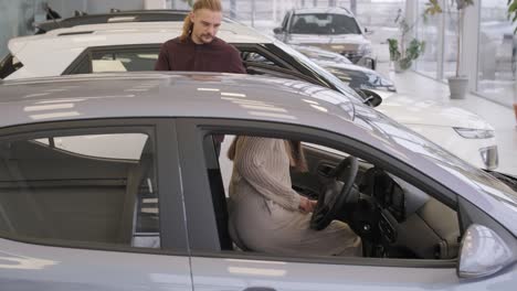 beautiful young couple at car showroom choosing a new car to buy.