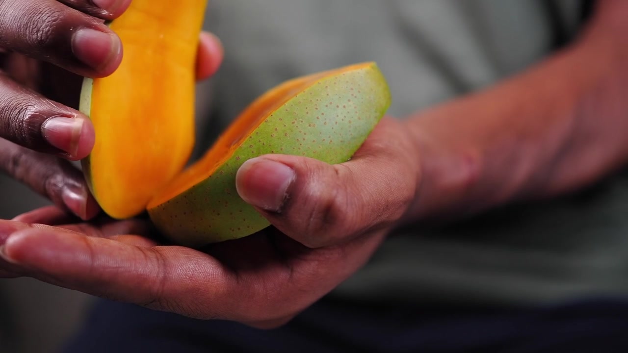 Persona che taglia un mango fresco e maturo con un coltello