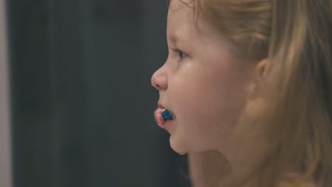 funny girl brushes teeth without paste in light bathroom