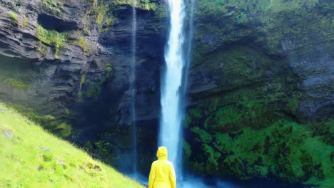 mujer parada frente a una hermosa cascada en islandia