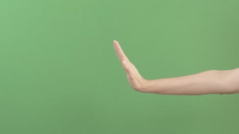 손의 제스처: 멈춰, 신호가 없습니다. 여성은 손을 고 제한 제스처를 만들고 녹색 화면에서 고립됩니다. 염색 키 배경: 방어, 불일치, 거부, 사회적 거리.