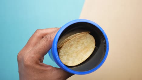 Hand-pick-chips-from-a-plastic-container-top-view