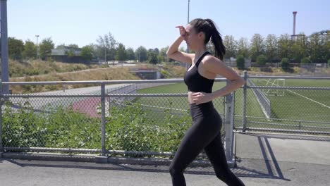 hermosa chica deportiva trotando al aire libre, tiro de seguimiento de vista lateral slomo