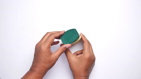 manos sosteniendo un recipiente con una tapa verde y amarilla