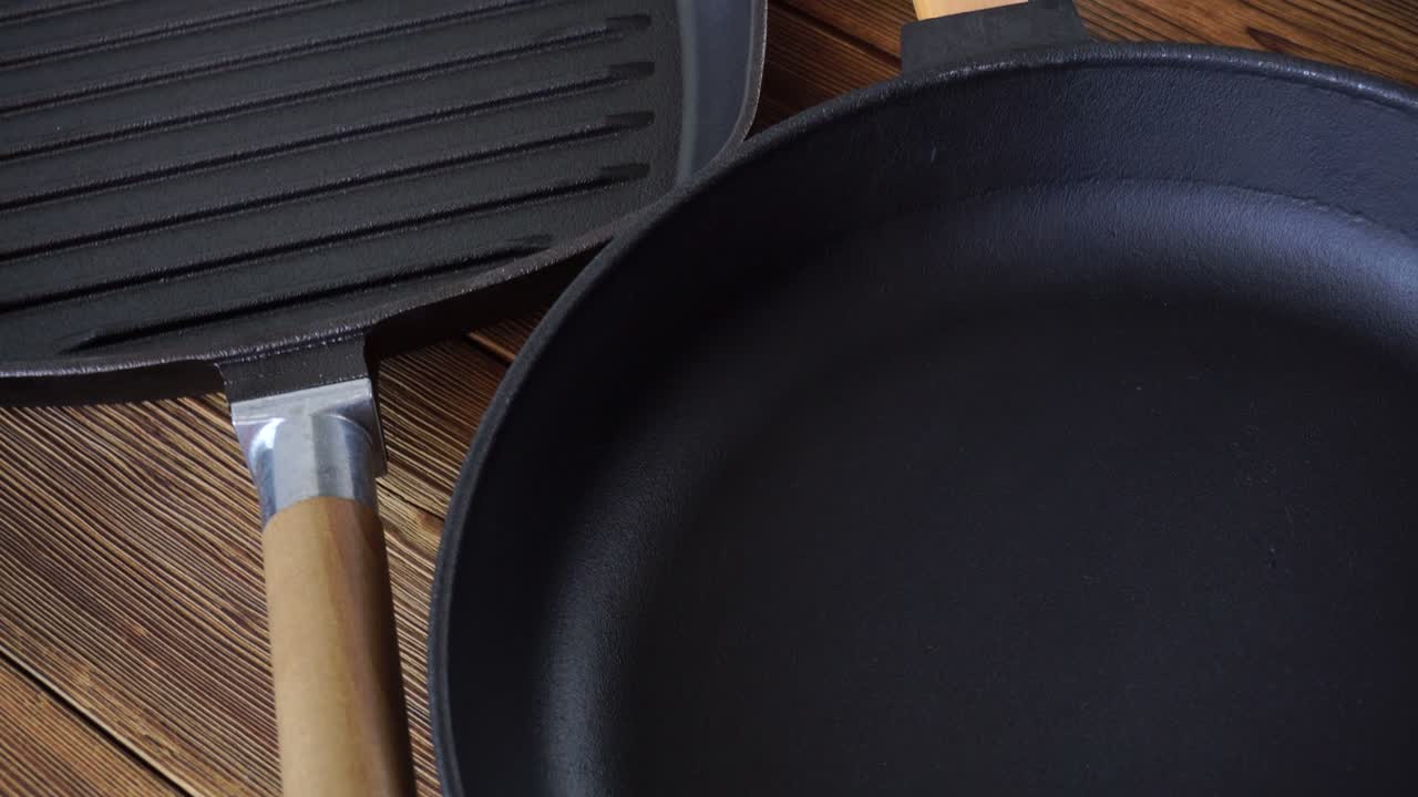 dos nuevas sartenes de hierro fundido antiadherentes sobre un fondo de madera. sartén de parrilla con mango de madera, accesorios de cocina