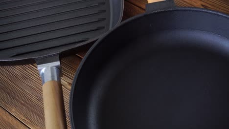 two new non-stick cast iron pans on a wooden background. grill pan with wooden handle, cooking accessories