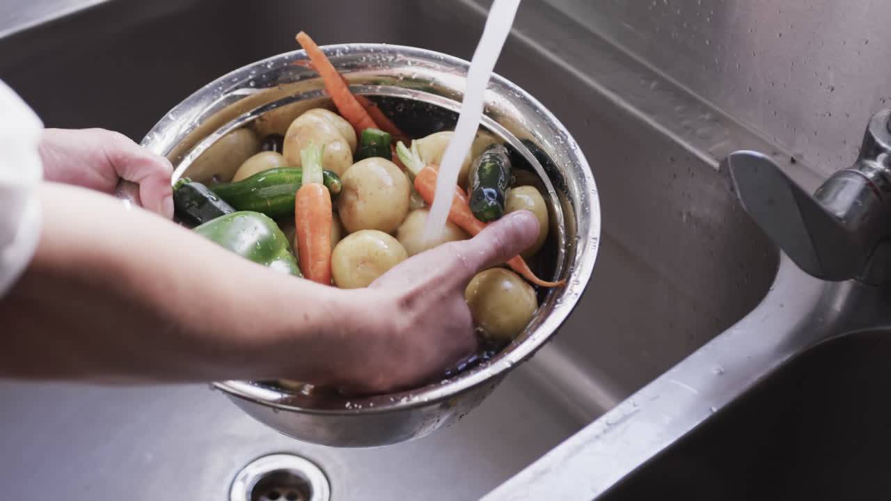 아프리카계 미국인 남성 셰프가 부에서 싱크대에서 채소를 고 있다.