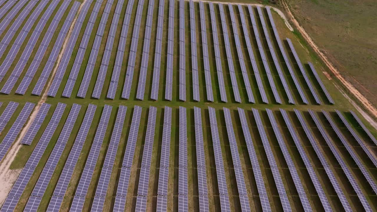Luftfoto af vedvarende solcelleanlæg i drift på åbent land