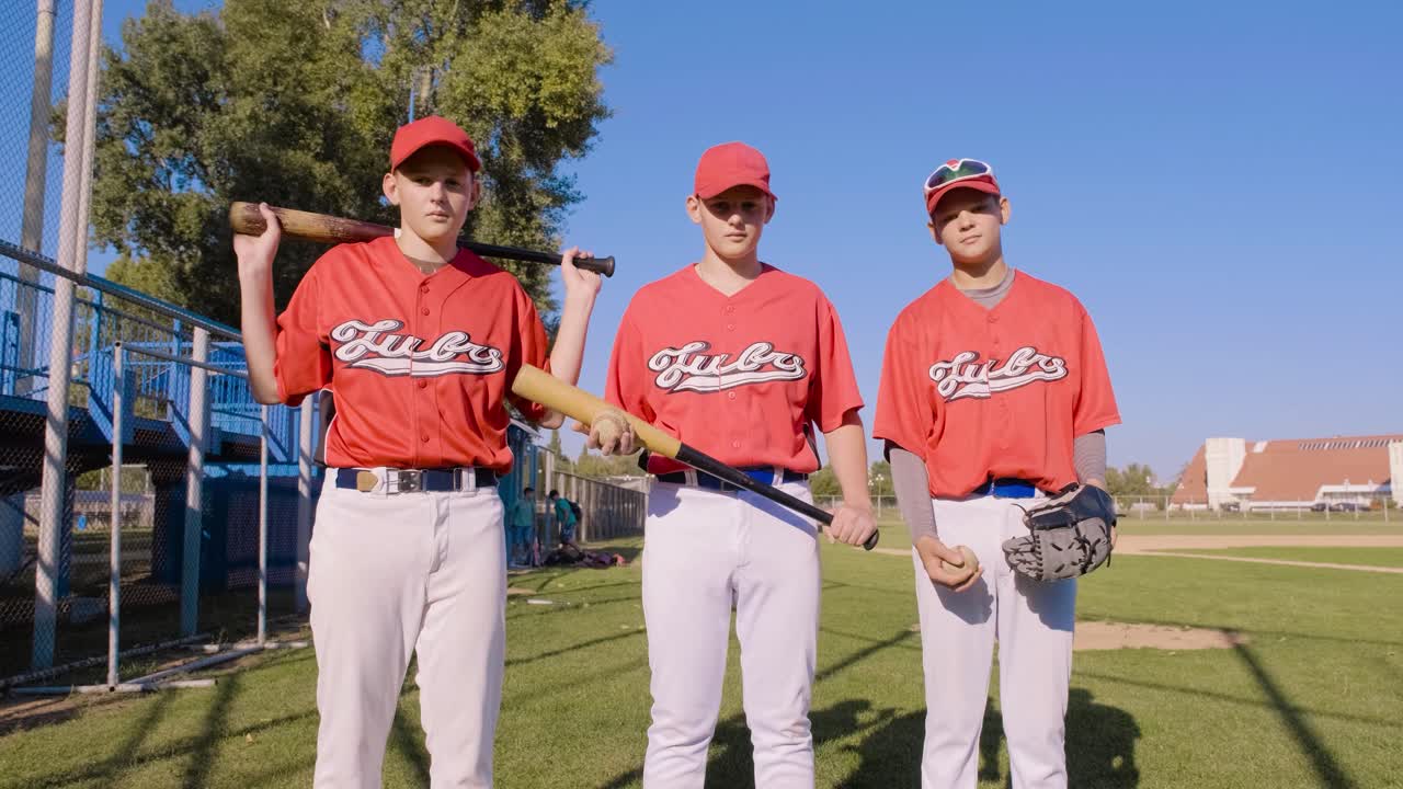 A youth baseball team happily posing together in their colorful uniforms at the field
