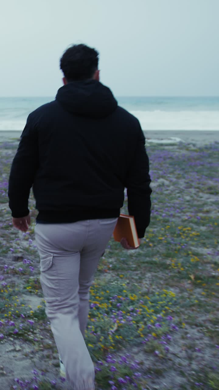 Man Walks Toward The Winter Sea With A Book In Hand