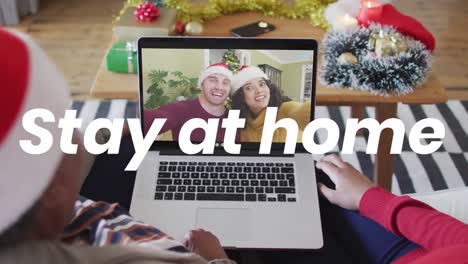 animation of stay at home text over diverse couple having video call with family