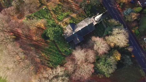 vista de pájaro sobre la iglesia rural de la campiña británica - colores otoñales en los árboles durante el amanecer