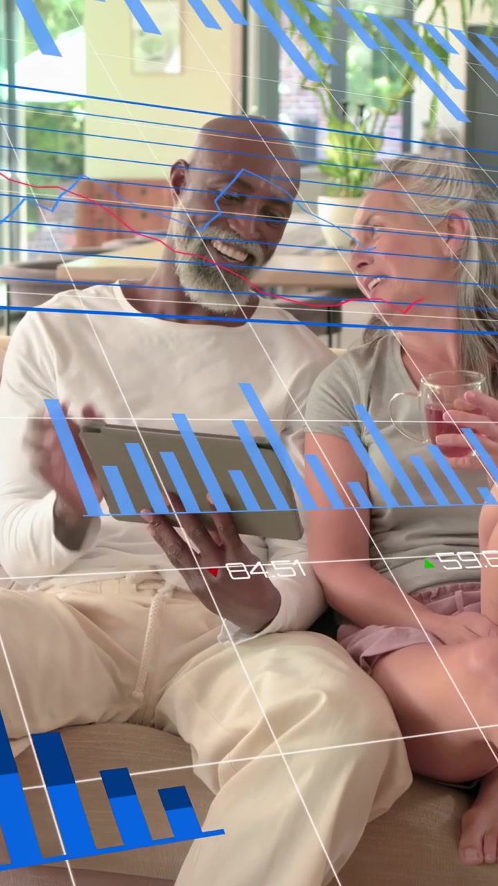 Vertical video: Couple tapping tablet on sofa, graphs moving over screen while checking finances