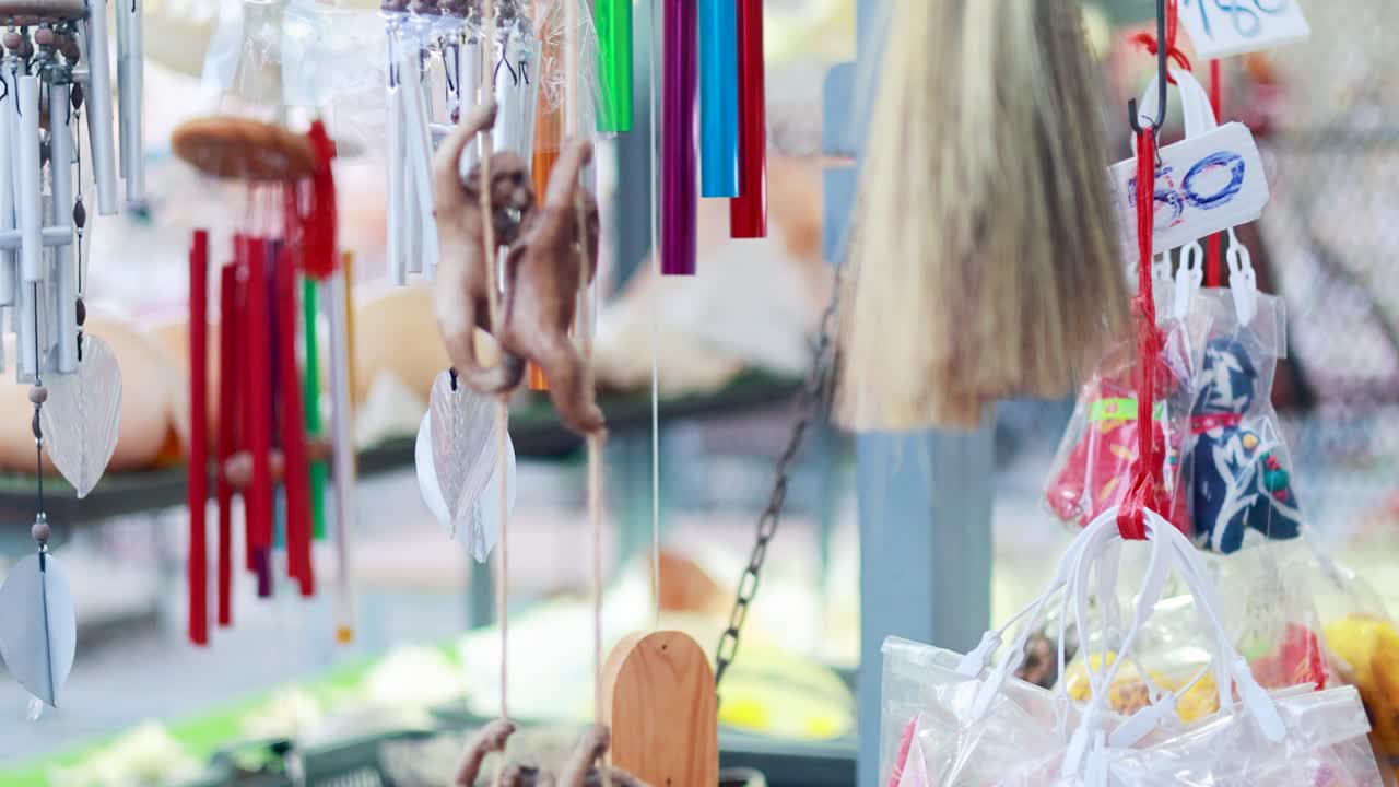 A monkey explores hanging decorations in a vibrant Phuket market, with colorful trinkets and lively atmosphere captured in natural light