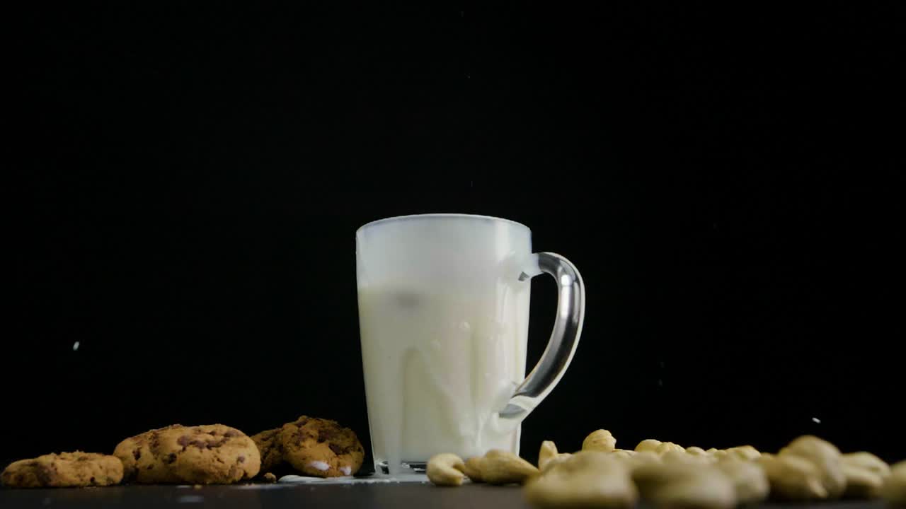 статичный снимок стакана, наполненного овсяным молоком, на боку печенье и орехи кешью