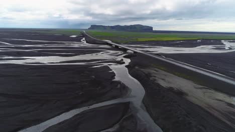 Antenne-Entlang-Einer-Straße-Und-Brücke-über-Ein-Großes-Dunkles-Vulkanisches-Hochwassersystem-In-Island