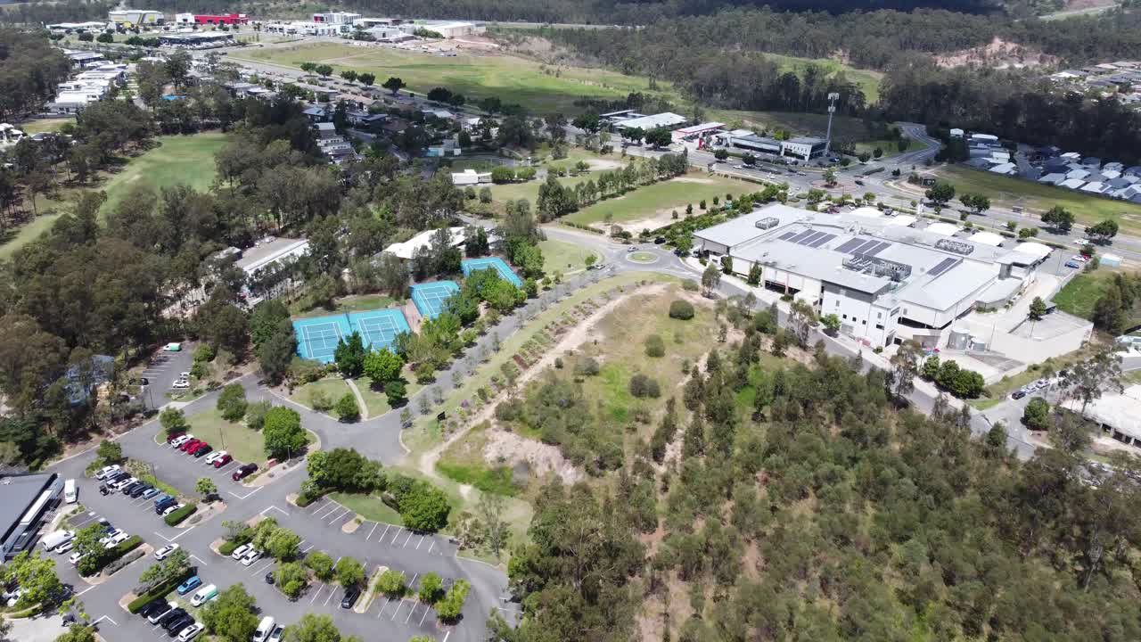 Drone flying towards 4 tennis courts and a small shopping complex in Australia