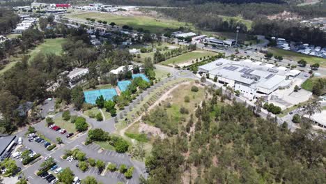 drone flying towards 4 tennis courts and a small shopping complex in australia