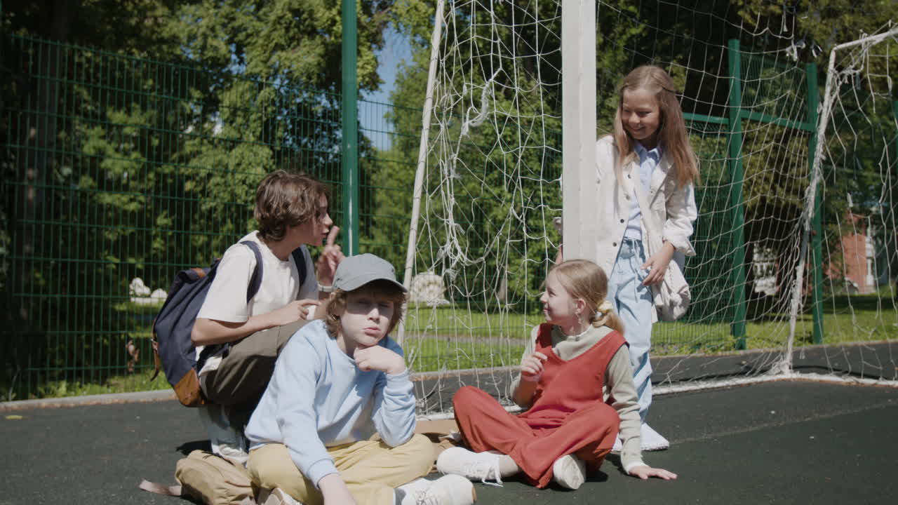 Group of happy children playing and talking on an outdoor sports court