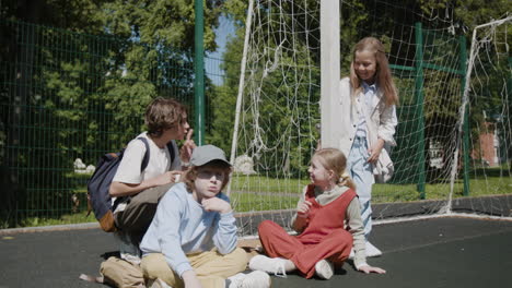 group of happy children playing and talking on an outdoor sports court