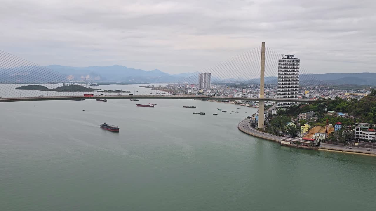 베트남의 안개 날 하롱 시의 바이 차이 다리 (bai chay bridge) 의 자동차 교통과 하롱 시에서 강물을 항해하는 화물선의 공중 전망
