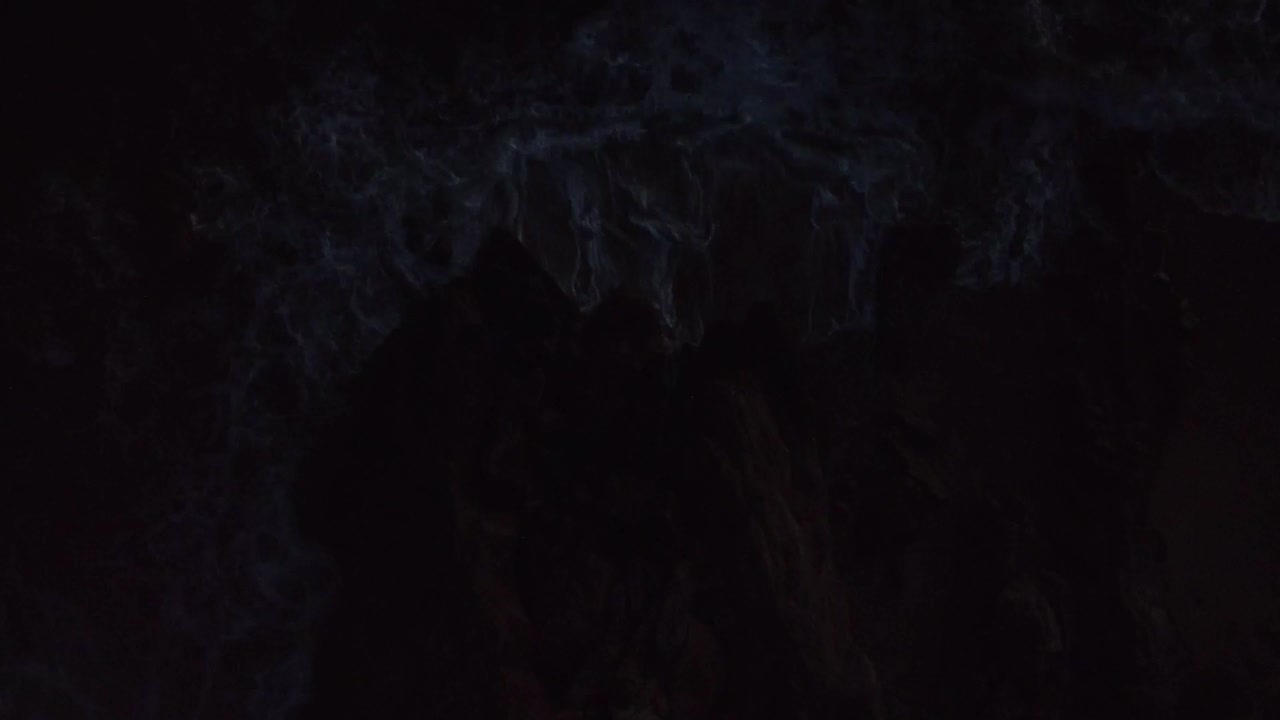 vista dall'alto, acqua che colpisce la roccia sulla spiaggia durante il tramonto