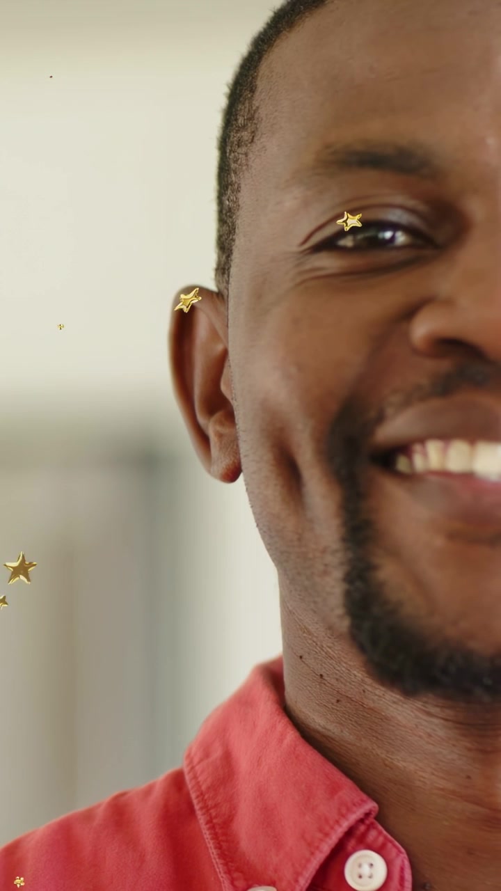 Vertical video: Close-up man reacting as gold confetti appear, smiling and laughing while marketing