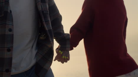 Woman-and-man-walking-on-sea-shore-at-sunrise.-Fashionable-couple-holding-hands