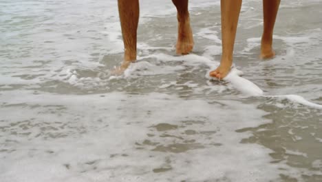 Low-section-of-couple-walking-with-hand-in-hand-on-the-beach-4k