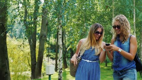amigos caminan por el parque y usan un teléfono inteligente