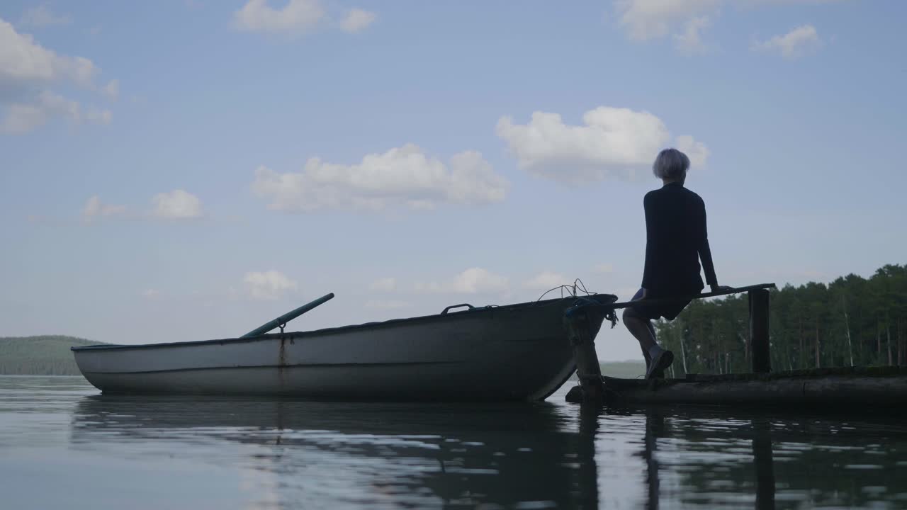 Woman sitting on a pier by a lake