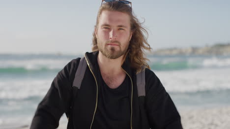 portrait of attractive caucasian man on beach removes sunglasses looking at camera serious relaxed blonde male warm summer seaside background