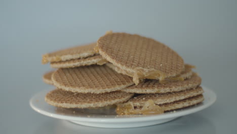 Montón-De-Stroopwafels,-Una-Típica-Galleta-Holandesa,-Sobre-Un-Plato-Blanco---Carro-Panorámico